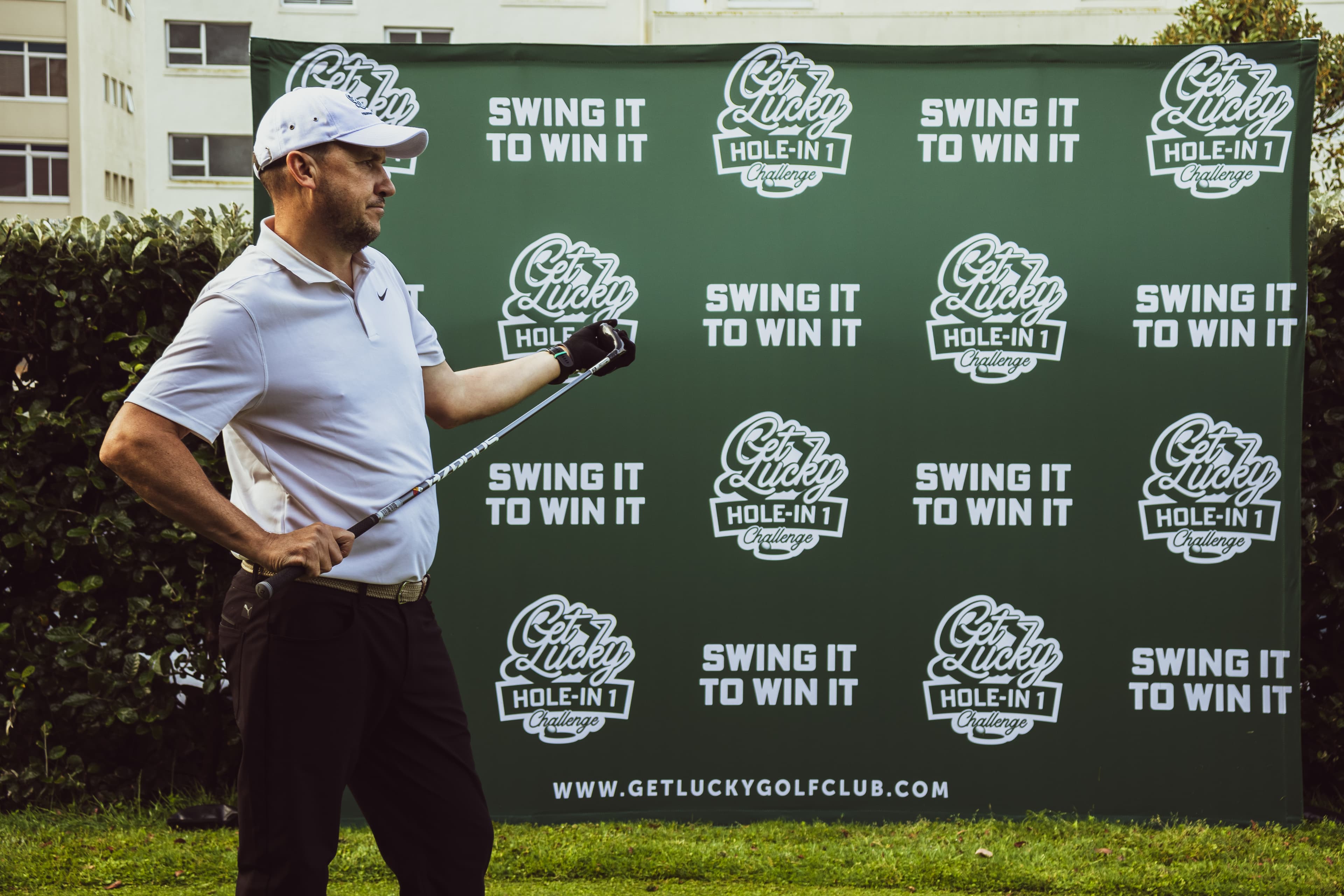 Golfer mid-swing in front of the Swing It To Win It backdrop